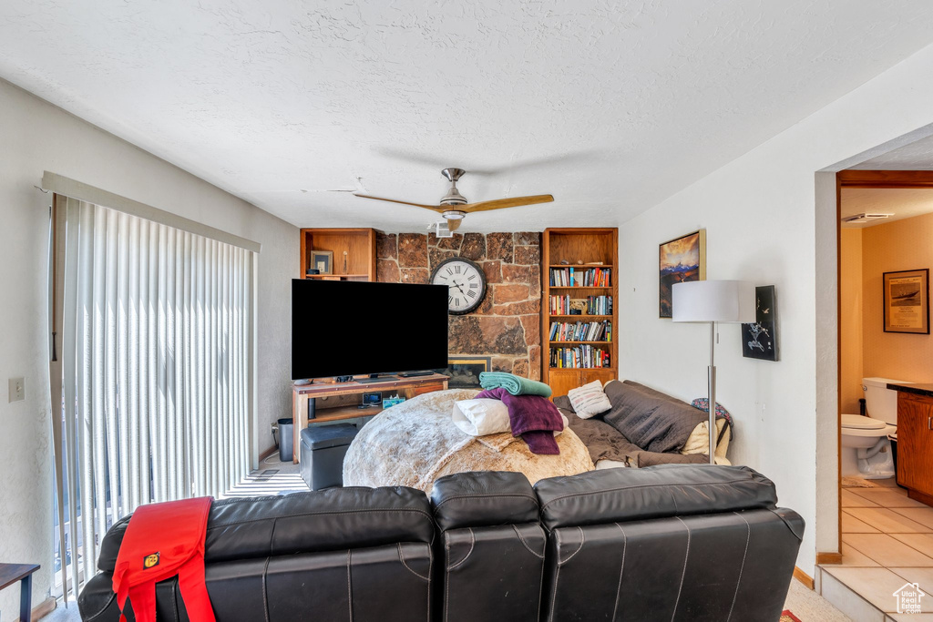 Tiled living area featuring a ceiling fan, a textured ceiling, and built in features