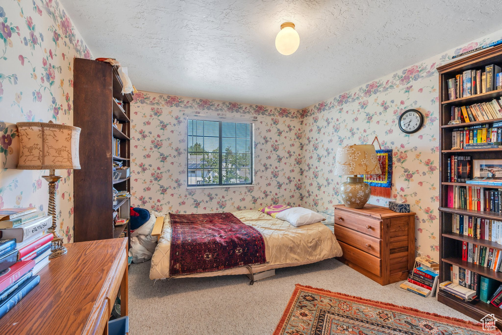 Carpeted bedroom with wallpapered walls and a textured ceiling