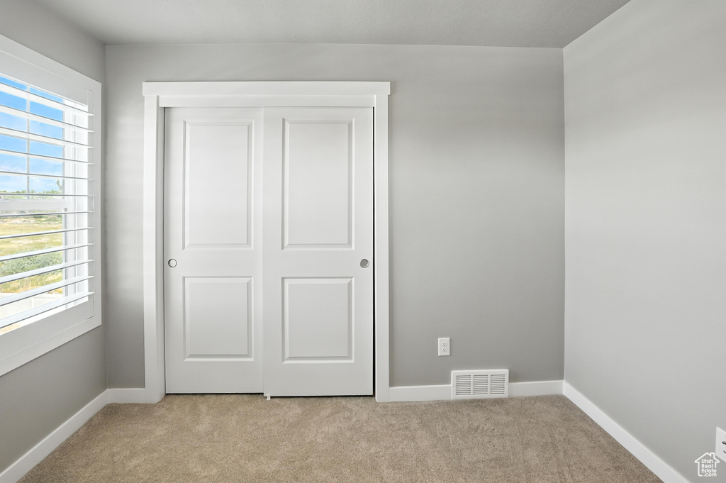 Unfurnished bedroom featuring light colored carpet and a closet