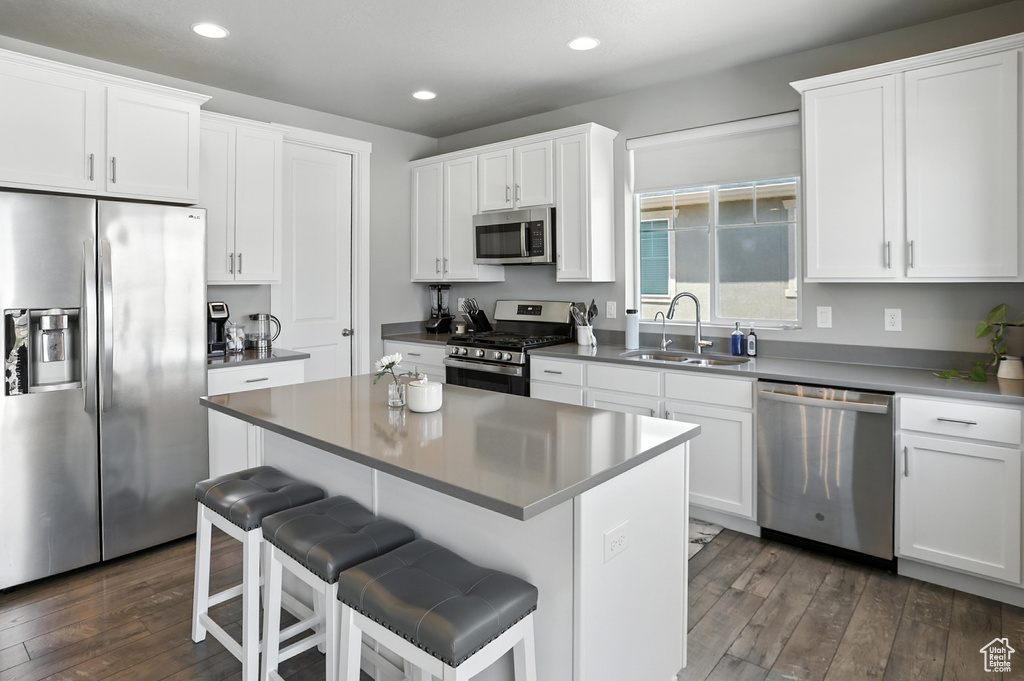 Kitchen featuring appliances with stainless steel finishes, dark wood-type flooring, a breakfast bar, recessed lighting, and a kitchen island