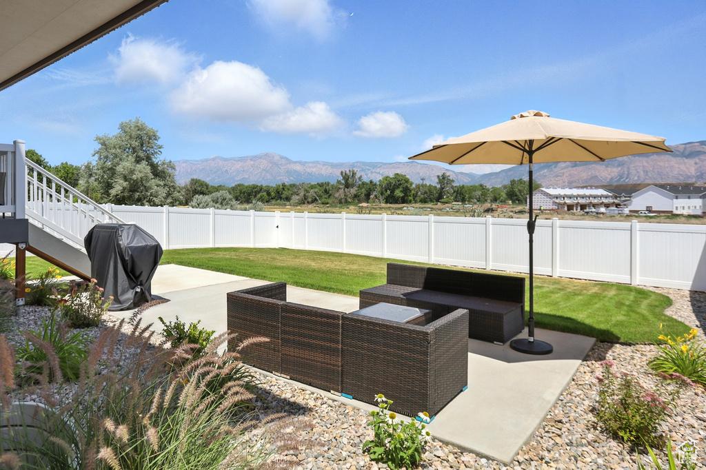 Fenced backyard with a mountain view, a patio area, a grill, and an outdoor hangout area