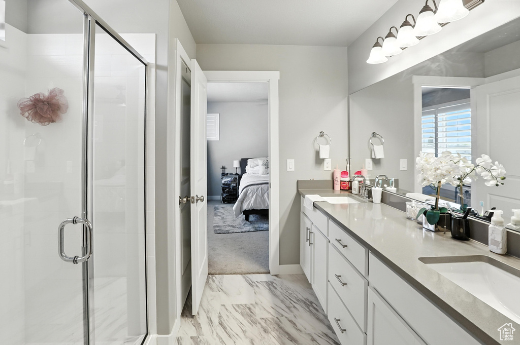 Full bath with ensuite bathroom, marble finish floors, double vanity, and a shower stall