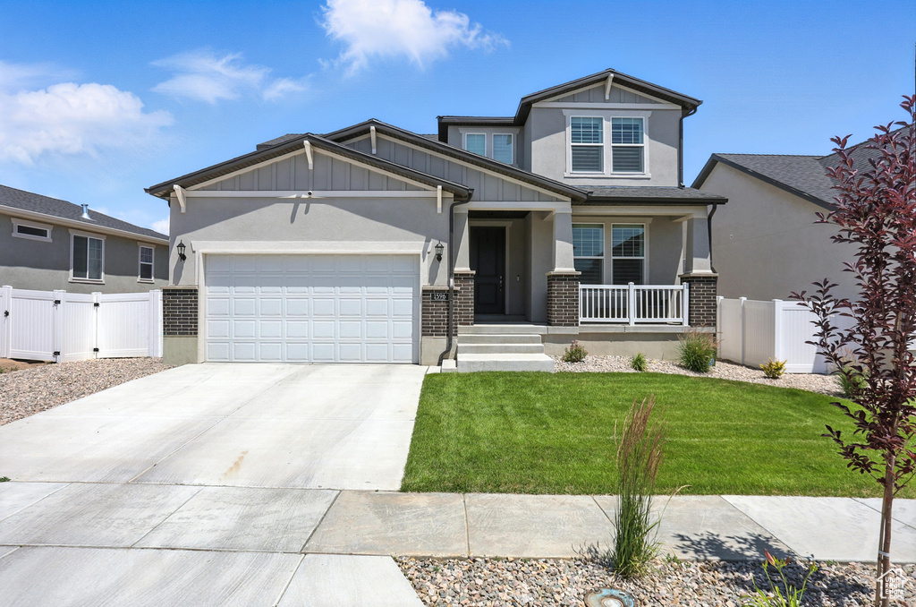 Craftsman-style home featuring covered porch, brick siding, driveway, and an attached garage
