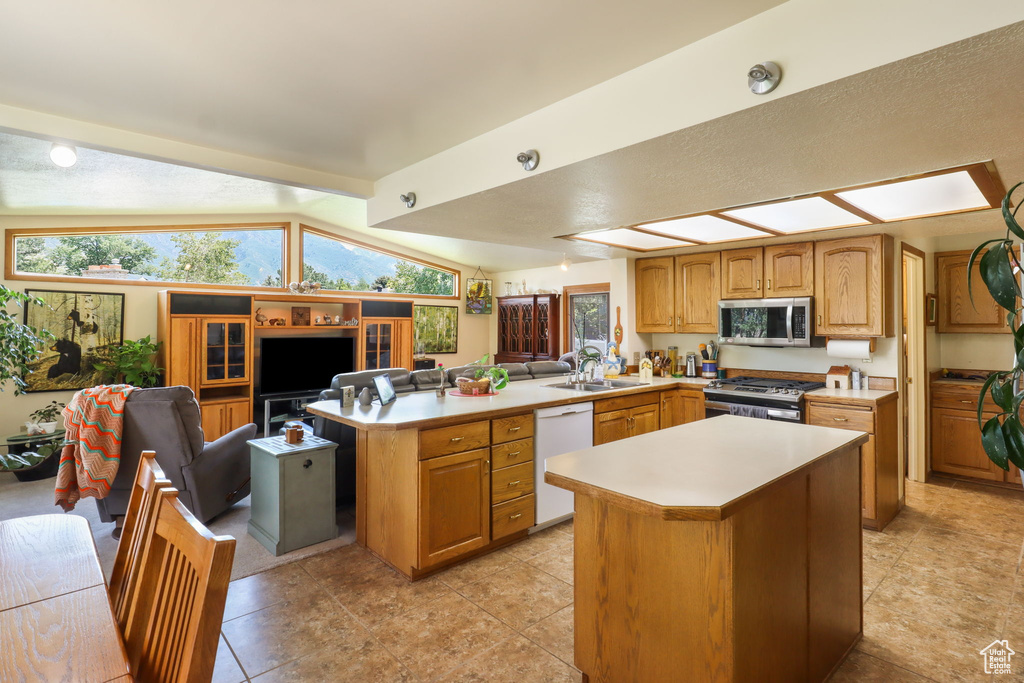 Kitchen featuring stainless steel appliances, a peninsula, light countertops, a center island, and open floor plan