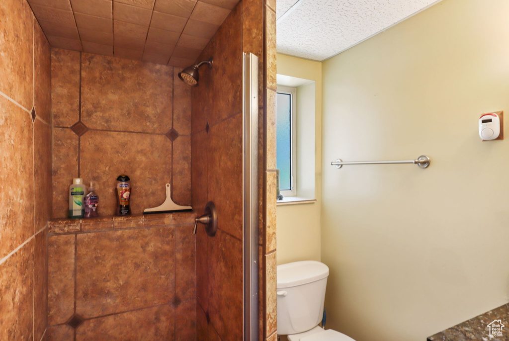 Full bath featuring toilet and tiled shower