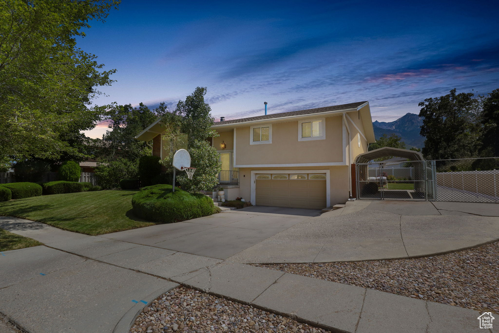 Split foyer home with a gate, stucco siding, driveway, and a garage
