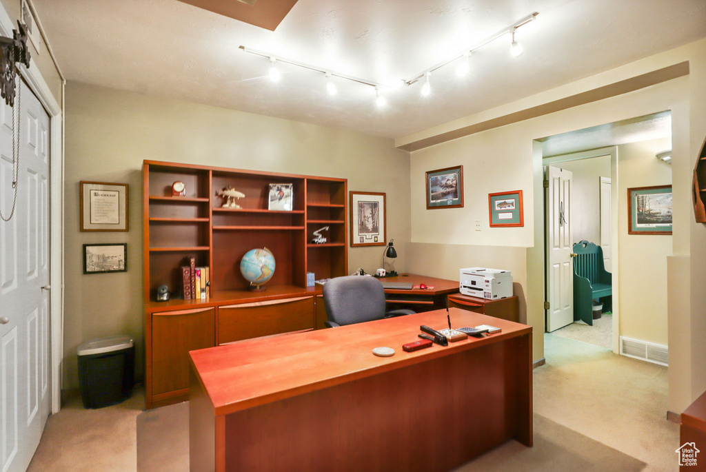 Home office featuring light carpet and track lighting