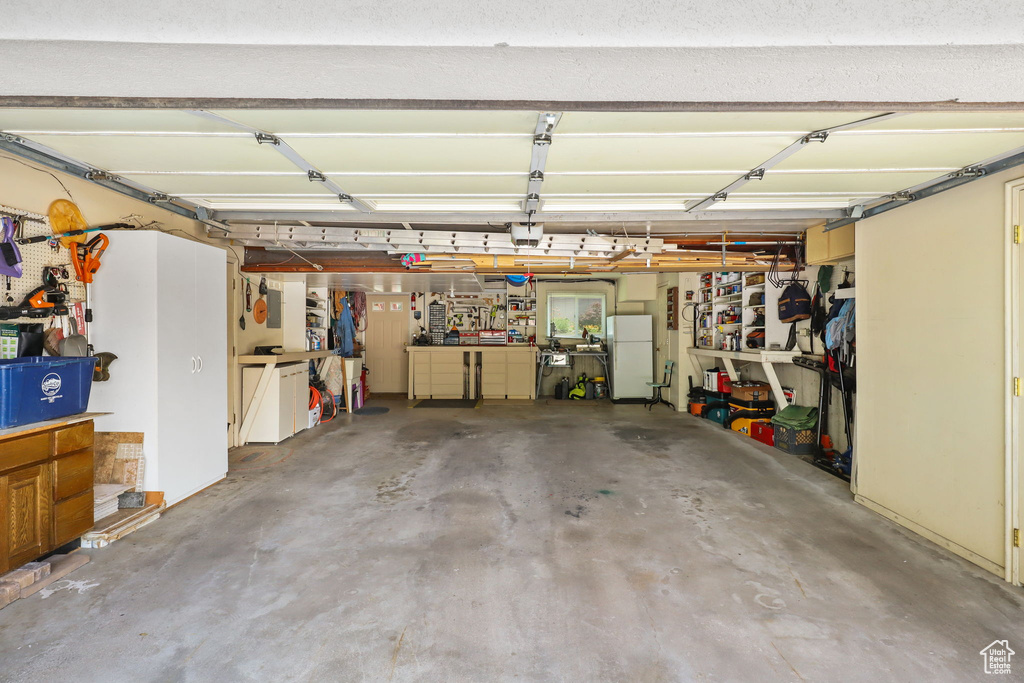 Garage featuring freestanding refrigerator and a garage door opener
