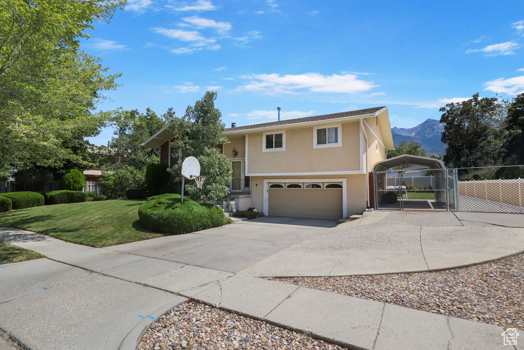 Split foyer home with a gate, stucco siding, concrete driveway, a garage, and a mountain view