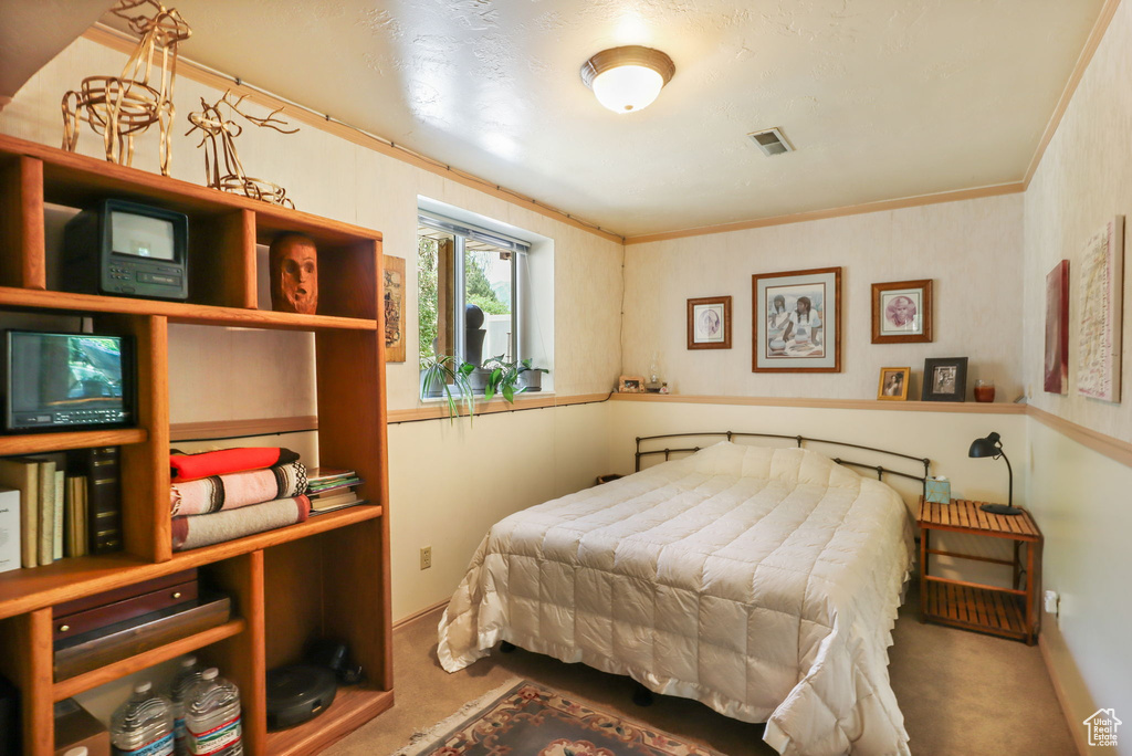 Carpeted bedroom featuring crown molding and baseboards