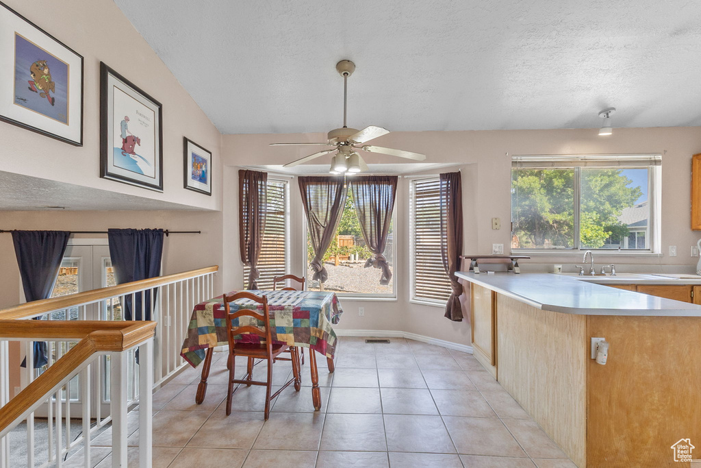 Dining area featuring a ceiling fan, light tile patterned floors, and a textured ceiling