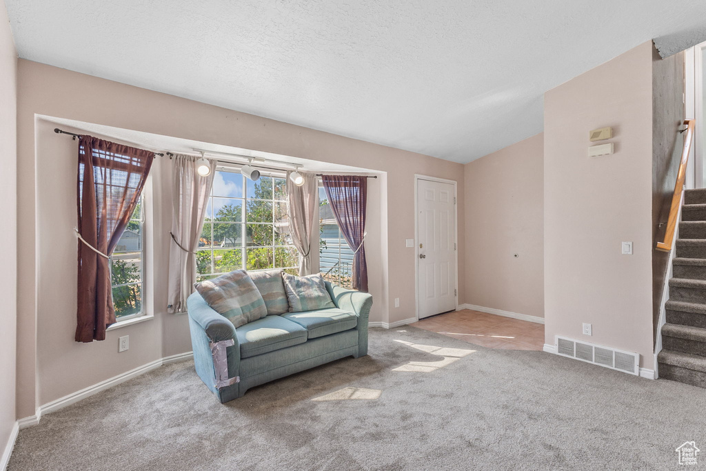 Carpeted living area with stairs and baseboards