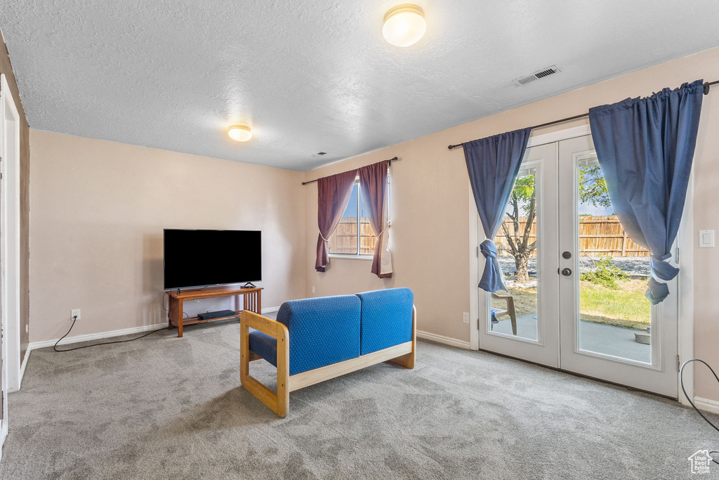 Living room featuring french doors, carpet, and a textured ceiling