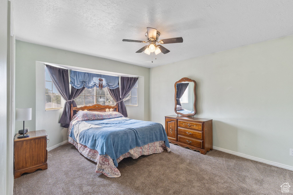 Carpeted bedroom featuring a textured ceiling and ceiling fan