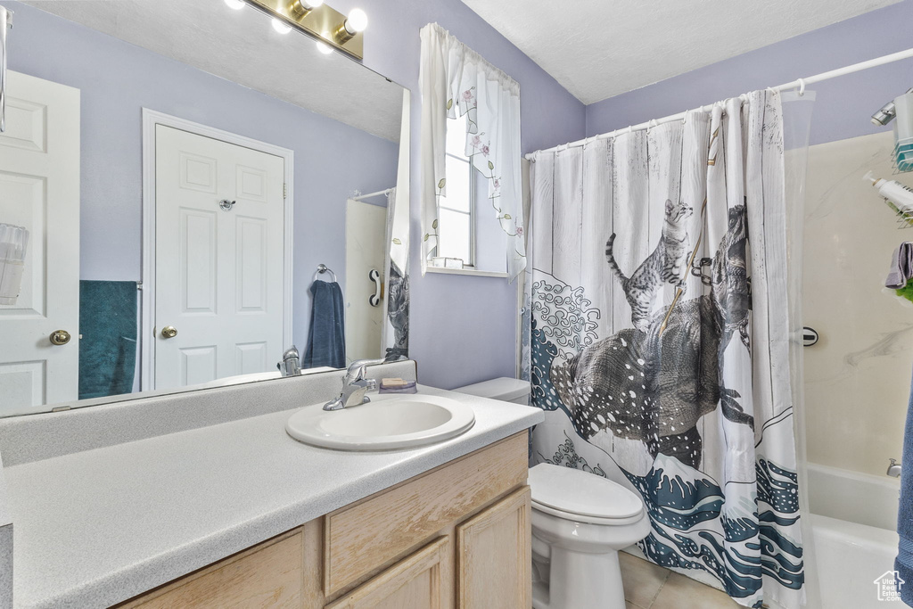 Bathroom featuring vanity, shower / bath combo with shower curtain, and tile patterned floors