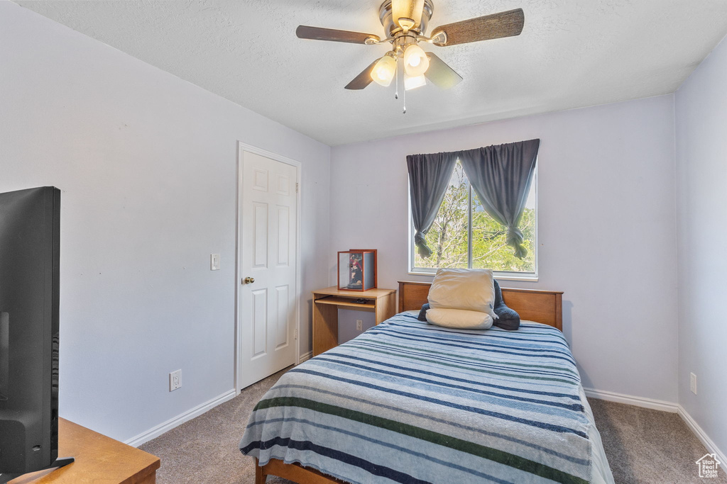 Carpeted bedroom featuring a textured ceiling and ceiling fan