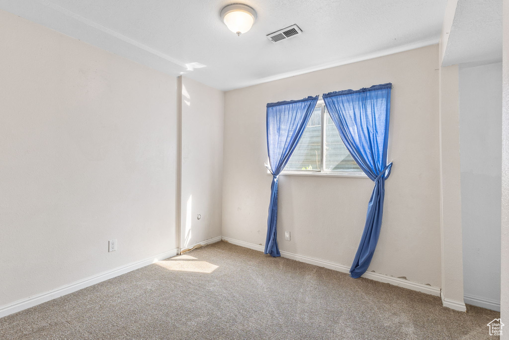 Carpeted spare room featuring baseboards