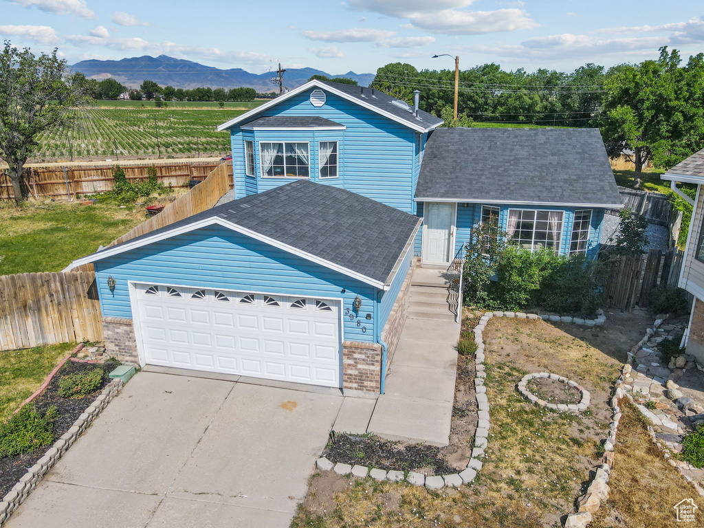 Traditional home with a mountain view, concrete driveway, a shingled roof, brick siding, and an attached garage
