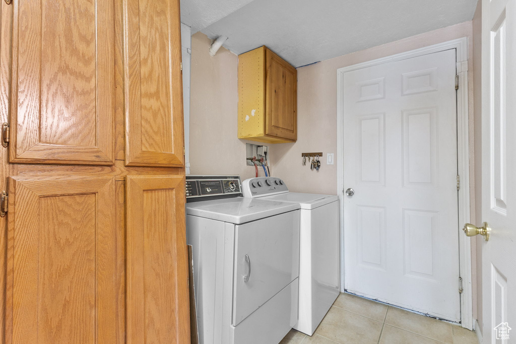 Laundry room featuring cabinet space, independent washer and dryer, and light tile patterned flooring