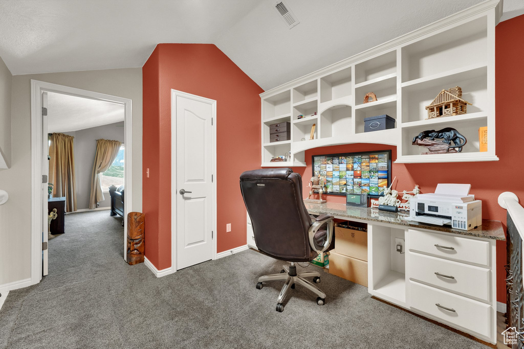 Home office with carpet floors and vaulted ceiling