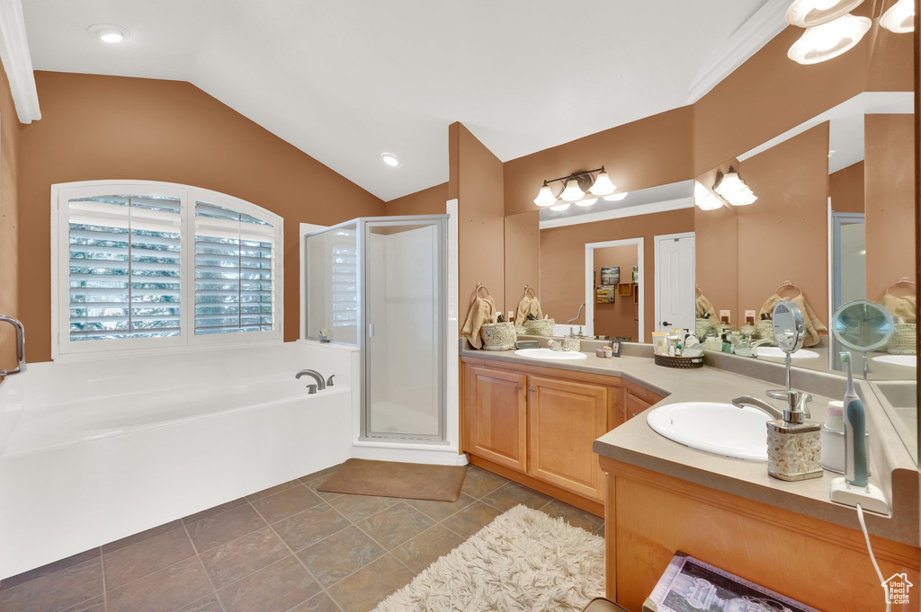 Bathroom featuring double vanity, a stall shower, a bath, vaulted ceiling, and tile patterned flooring