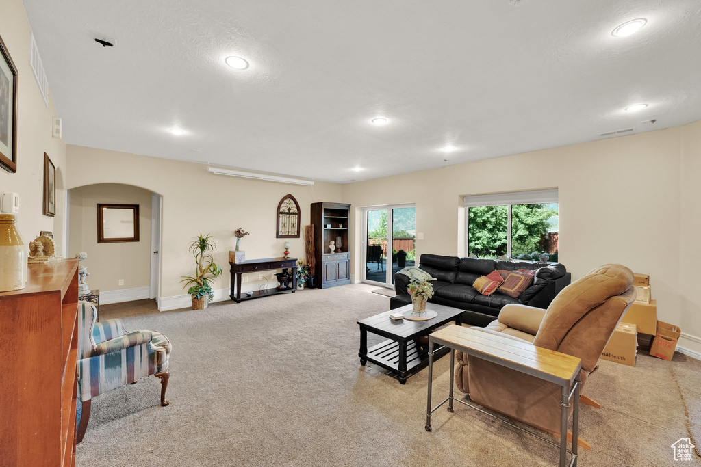 Living area with light carpet, recessed lighting, and arched walkways