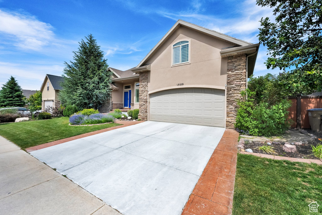 View of front facade featuring stone siding, stucco siding, driveway, and a garage