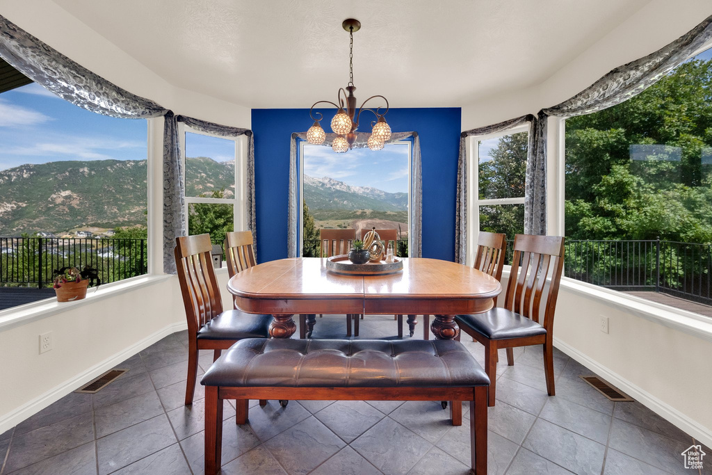 Tiled dining area featuring plenty of natural light, a chandelier, and a mountain view
