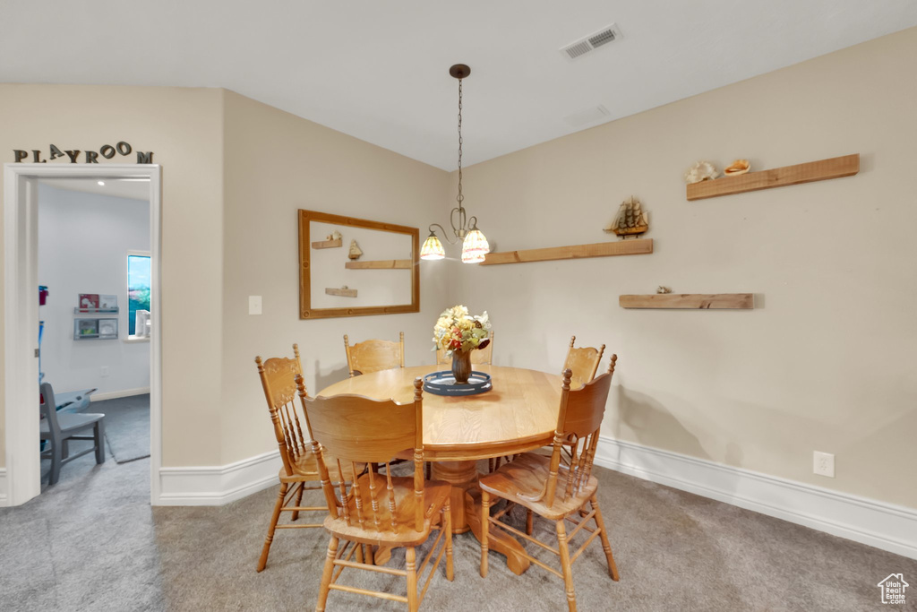 Carpeted dining space featuring baseboards and a chandelier