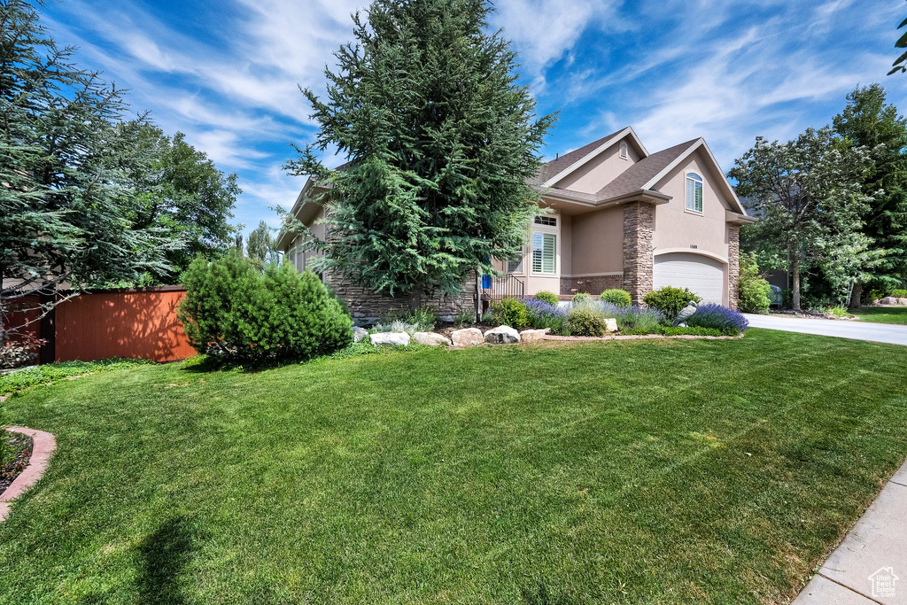 Obstructed view of property featuring an attached garage, stone siding, stucco siding, and driveway