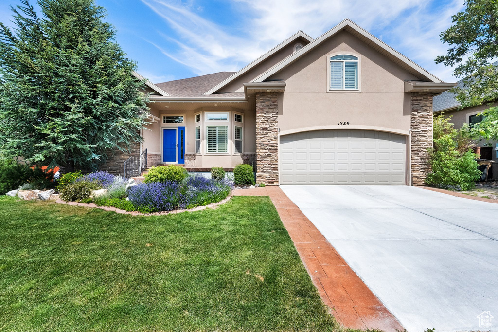 View of front of house featuring stone siding, stucco siding, concrete driveway, a front lawn, and a shingled roof