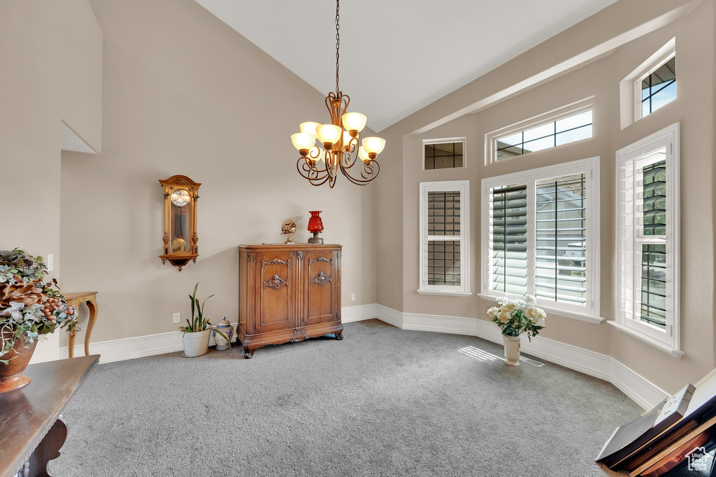 Living area featuring carpet, high vaulted ceiling, a chandelier, and plenty of natural light