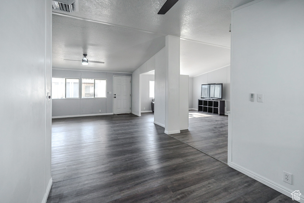 Empty room featuring a ceiling fan, a textured ceiling, and dark wood-style flooring