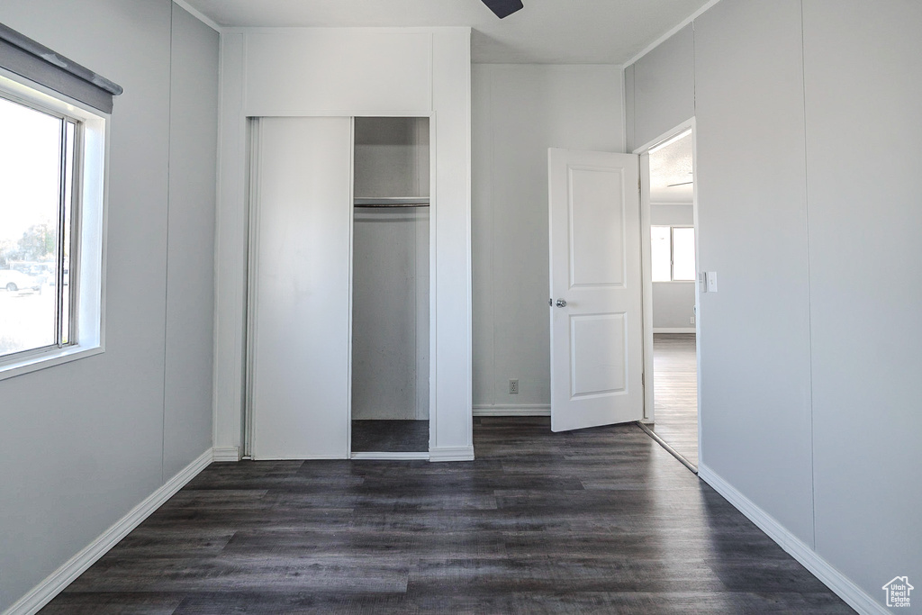 Unfurnished bedroom featuring dark wood finished floors, multiple windows, and a closet