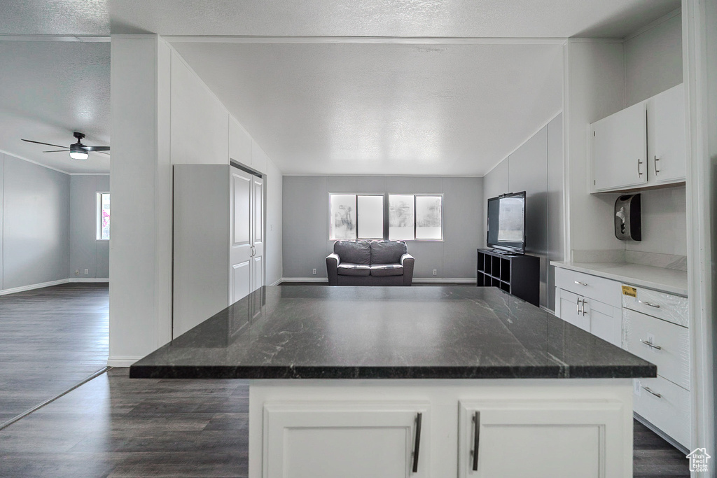 Kitchen featuring open floor plan, white cabinets, dark wood-type flooring, a ceiling fan, and a textured ceiling
