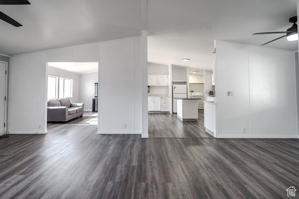 Living room featuring a ceiling fan, dark wood finished floors, and lofted ceiling