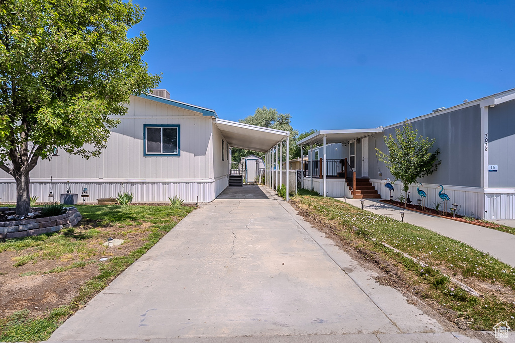 View of front facade featuring concrete driveway, a storage unit, and an attached carport