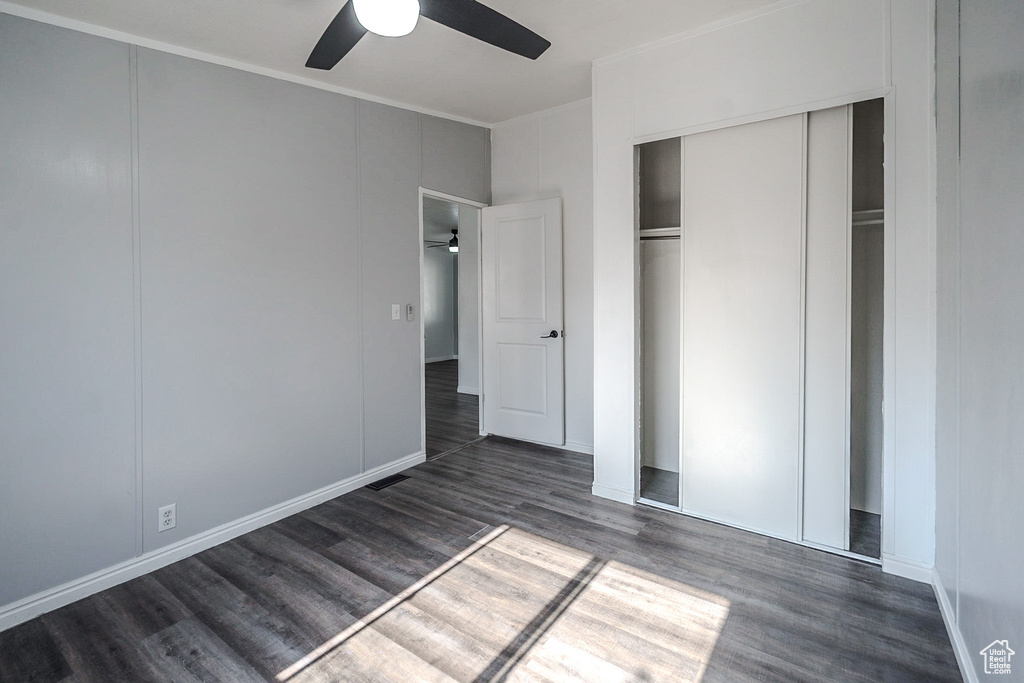 Unfurnished bedroom with wood finished floors, ornamental molding, a closet, and a ceiling fan