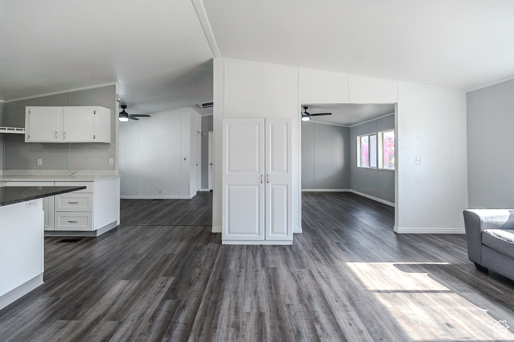 Unfurnished living room featuring ceiling fan, dark wood-style floors, and lofted ceiling