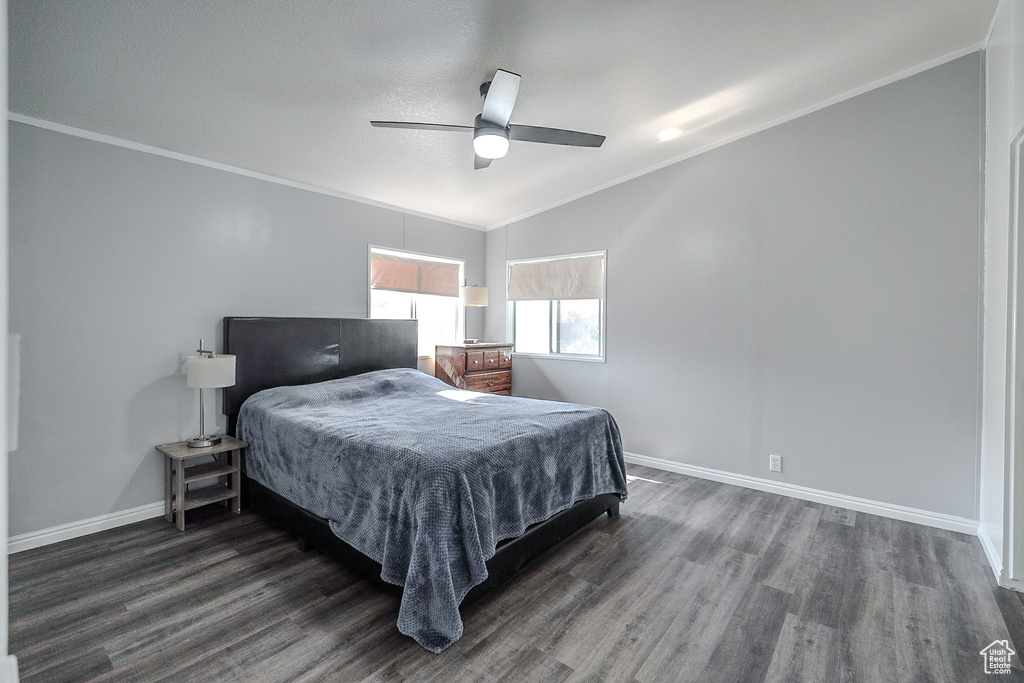 Bedroom featuring lofted ceiling, dark wood-style floors, crown molding, and ceiling fan