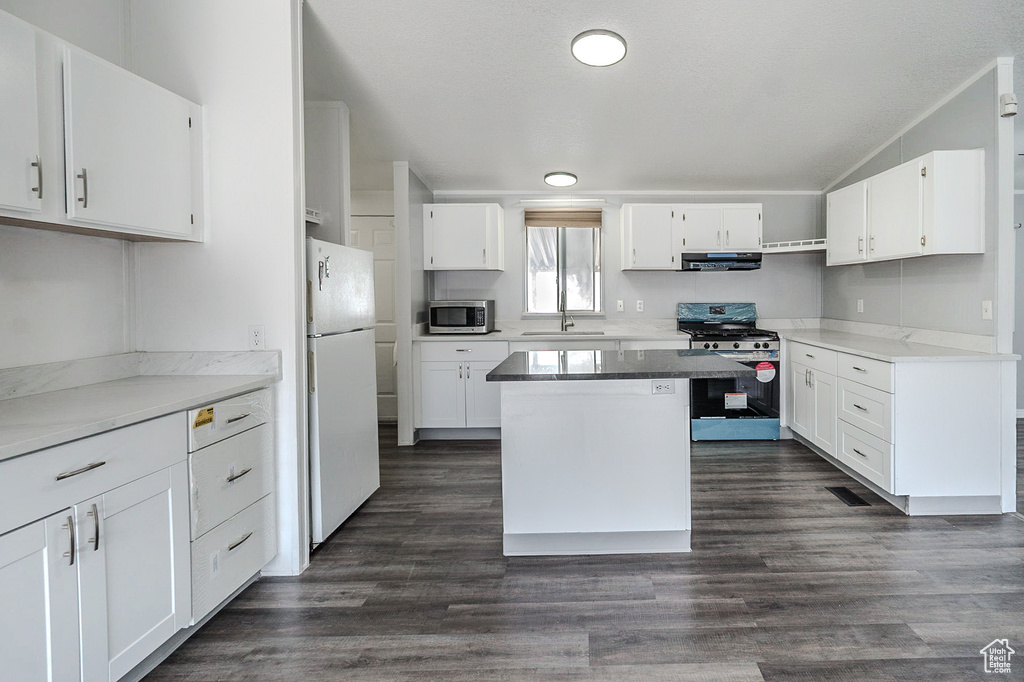Kitchen featuring stainless steel appliances, under cabinet range hood, white cabinets, and lofted ceiling