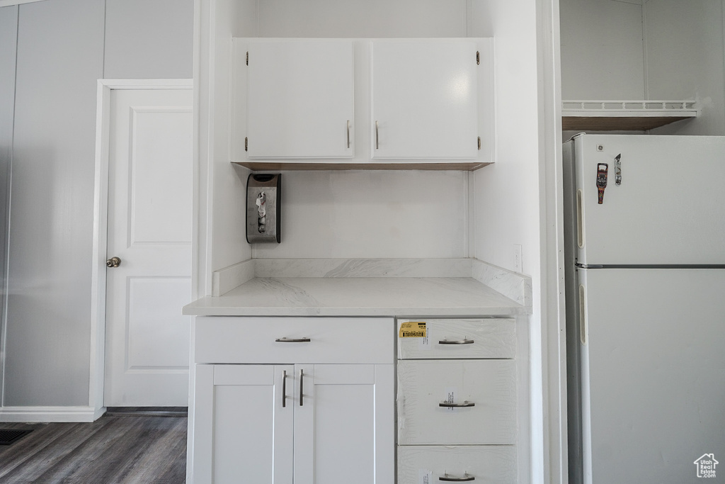 Kitchen featuring freestanding refrigerator, white cabinets, and dark wood finished floors