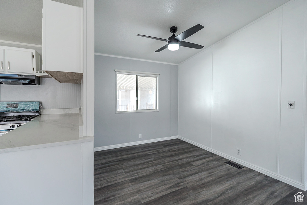 Unfurnished dining area with a ceiling fan, dark wood finished floors, and crown molding