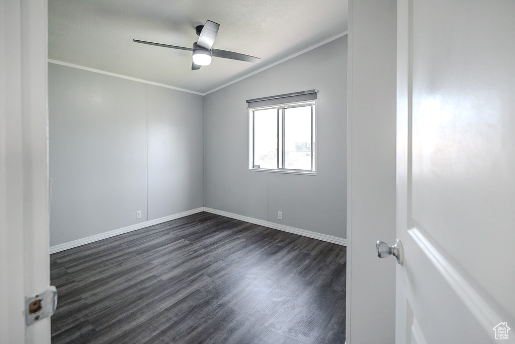 Empty room with ornamental molding, dark wood finished floors, ceiling fan, and lofted ceiling