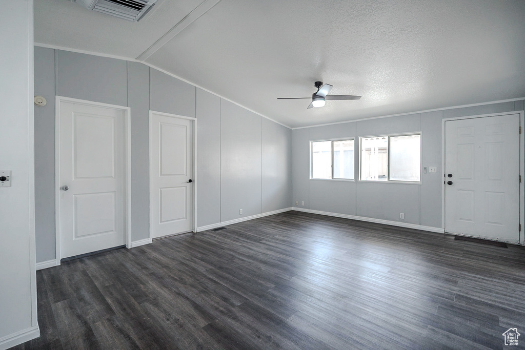 Spare room with ceiling fan, vaulted ceiling, dark wood finished floors, and crown molding