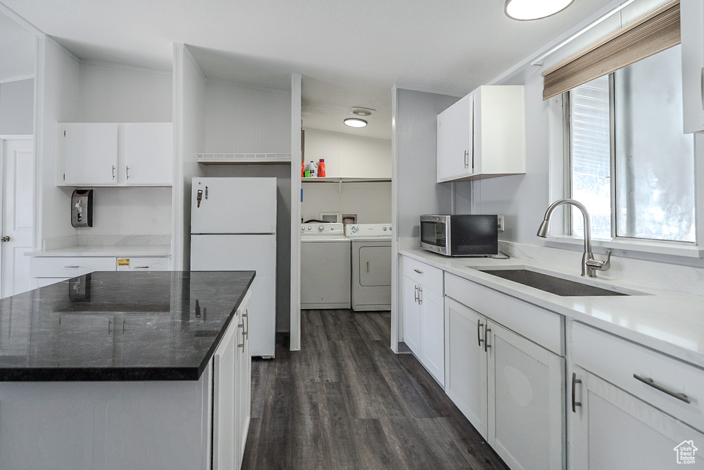 Kitchen featuring washer and dryer, freestanding refrigerator, stainless steel microwave, white cabinets, and dark wood-style flooring