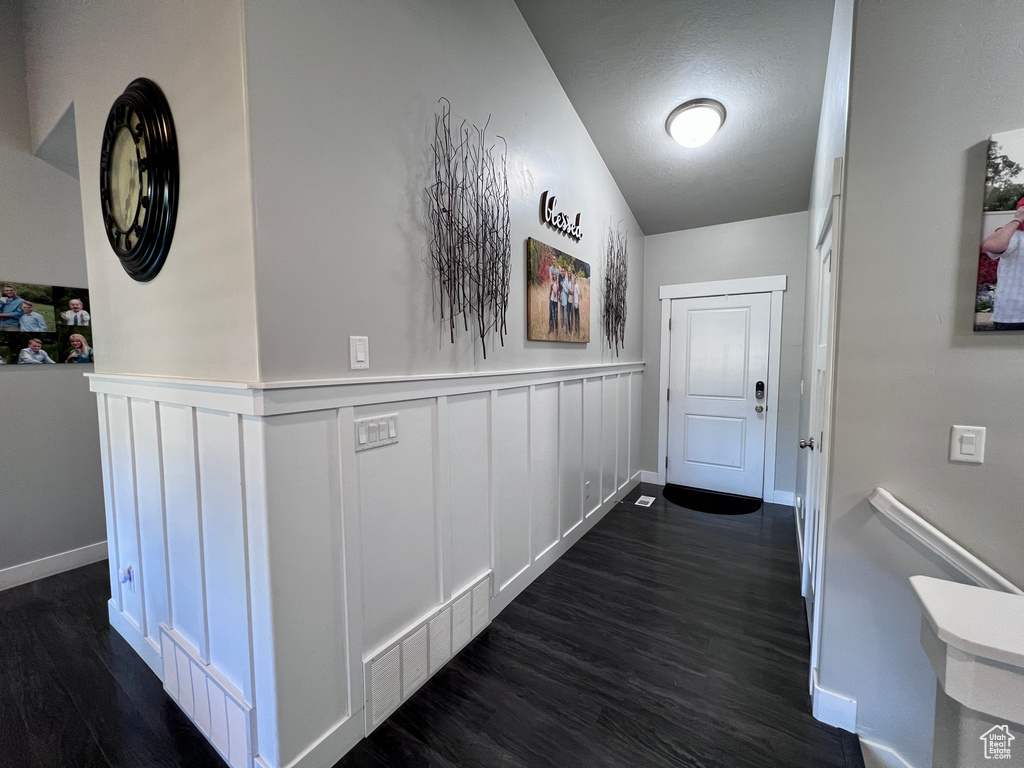 Hallway featuring dark wood finished floors and a wainscoted wall