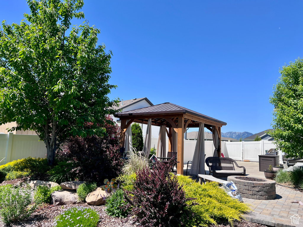 Fenced backyard featuring a gazebo, an outdoor fire pit, and a patio
