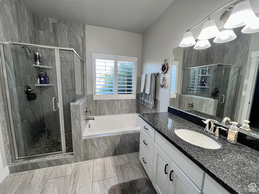 Bathroom featuring vanity, a garden tub, a shower stall, and a chandelier