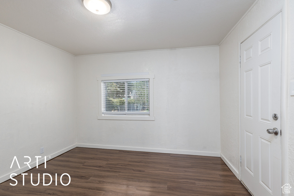 Empty room featuring dark wood finished floors and ornamental molding